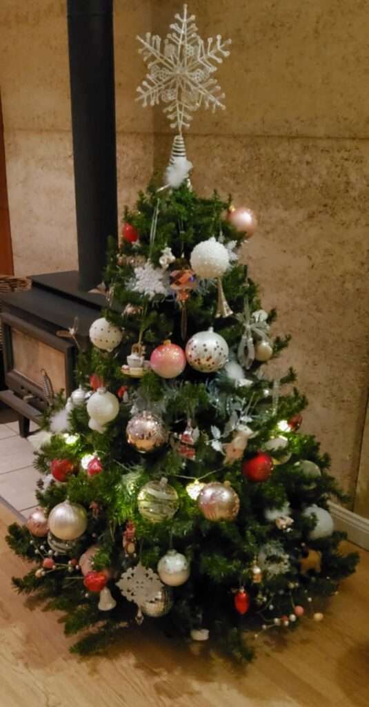 A pretty Christmas tree in an Australian home covered in mostly pink & white ornaments with touches of red, complete with small lights and a white star on top.